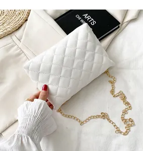 Detailed view of a white quilted crossbody bag with a sleek gold chain strap held by hand