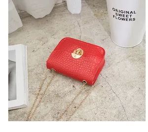 Dettaglio di una mini borsa a tracolla rossa con motivo a pietra e catena dorata