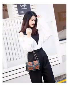 Detailed view of a chic snake skin crossbody bag with gold chain strap on model