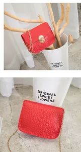 Dettaglio di una piccola borsa rossa con trama coccodrillo e catena dorata chic