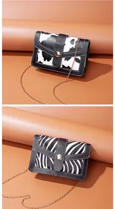 Detail view of stylish small square bags with cow and zebra animal prints and chains.