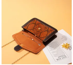 Detailed view of open snake print crossbody bag revealing brown interior and magnetic closure