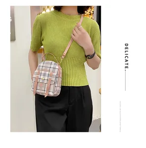 Stylish woman carrying a small plaid checkered crossbody bag with pink adjustable straps