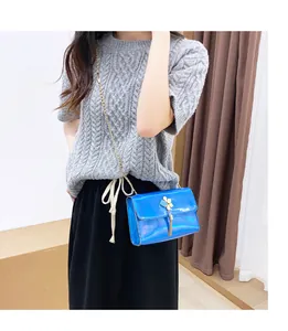 Detail showing a blue holographic crossbody bag with gold tassel decor on a model
