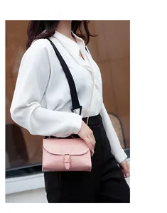 Close-up detail of pink crocodile pattern crossbody bag with chain strap on model
