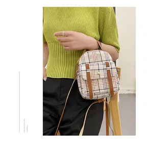 Detailed macro view of a fashionable plaid mini backpack held by a model in a green top.