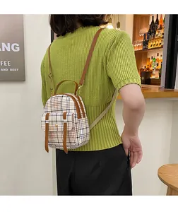 Back view of a woman wearing a stylish small plaid backpack with brown straps.