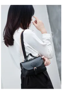 Elegant black croc-embossed crossbody bag with gold chain strap shown on a model