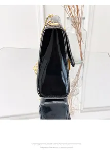 Side view of black patent leather crossbody bag with gold fringe tassel details.
