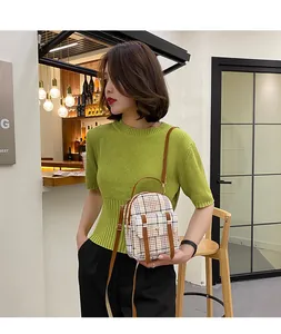 Stylish plaid mini backpack crossbody bag shown on model in a casual indoor setting