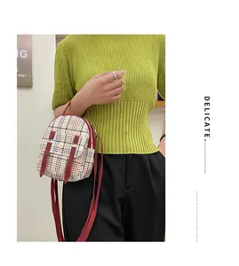 Detail view of a stylish plaid mini backpack with red straps worn by a fashion model