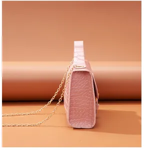 Side view detail of a pink crocodile pattern square handbag with gold chain strap