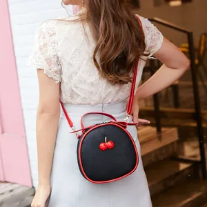 Fashionable round black lychee grain crossbody bag with red cherry charm and strap