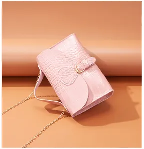 Detailed view of pink crocodile embossed leather bag with gold buckle and metal chain