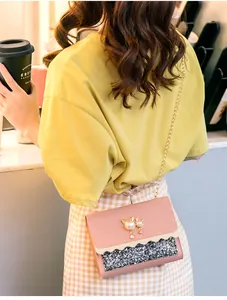 Detail view of a stylish pink mini bag with cat pearl decoration worn on person