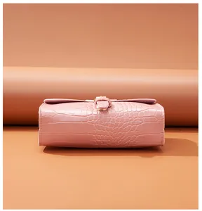Macro view of pink crocodile embossed texture on a women's small square crossbody bag