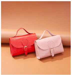 Crocodile embossed square handbags in red and pink displayed on warm background