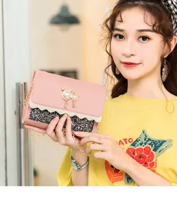 Close-up of a pink and glittery women's chain shoulder bag held by a model.