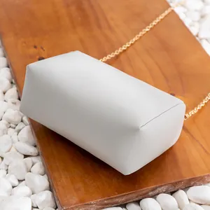 Elegante borsa a tracolla rettangolare grigio chiaro con catena su legno e ciottoli bianchi