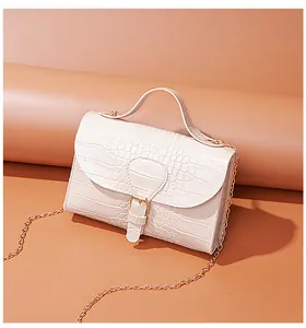 Side view of an elegant cream crocodile pattern small crossbody flap bag with chain strap