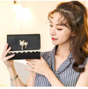 Asian model holding a black small crossbody chain bag with cat pearl ornament detail