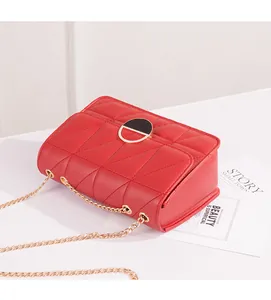 Primo piano di una borsa a tracolla trapuntata rossa con catena dorata e chiusura a cerchio.