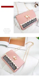 Detailed view of pink crossbody bag with pearl cat ornament and glitter wave pattern.