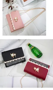 Detail of small crossbody bag featuring cat pearl hardware and glitter wavy trim.