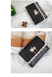 Detailed view of a black crossbody chain bag with pearl cat ornament and glitter flap.