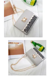 Detailed view of a grey small square chain bag with pearl cat buckle and glitter wavy trim