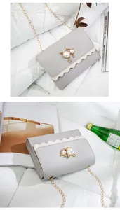 Detail view of elegant grey crossbody bag featuring a pearl cat ornament and gold chain.