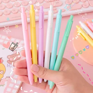 Set of macaron colored retractable gel pens held in hand against pink background