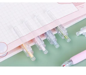 Close-up of macaron colored retractable gel pens clipped to a pink grid notebook.