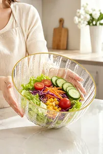 Gros plan d'un saladier en verre strié avec bord doré et légumes frais variés.