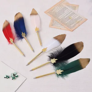 Varietà di eleganti penne a sfera con piume e accenti in foglia d'oro.
