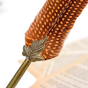 Close-up of vintage feather quill pen with bronze leaf detail and spotted feather texture.
