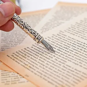 Détail d'une plume d'oie vintage en argent tenue sur un livre ouvert avec texte.