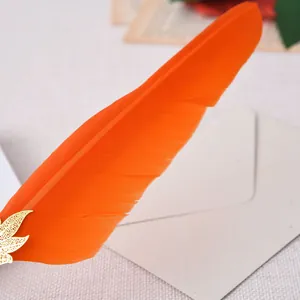 Gros plan d'une plume d'oie orange vif avec un ornement décoratif en métal en forme de feuille
