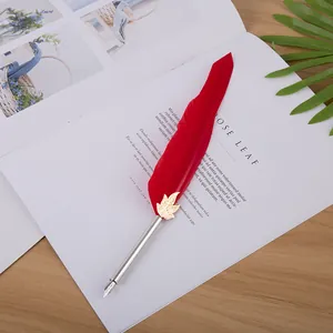 Détail d'un stylo plume élégant en plume rouge sur une page de magazine ouverte.