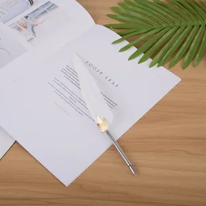 Vue détaillée d'un stylo plume en plume blanche avec un accent de feuille dorée.
