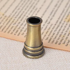 Primer plano de un soporte para bolígrafo de bronce antiguo con anillos decorativos