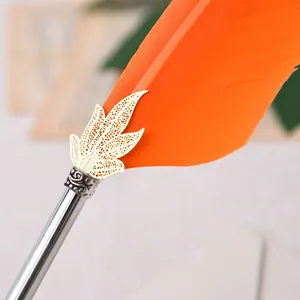 Détail d'un stylo plume orange avec ornement feuille d'or et tige métallique vintage