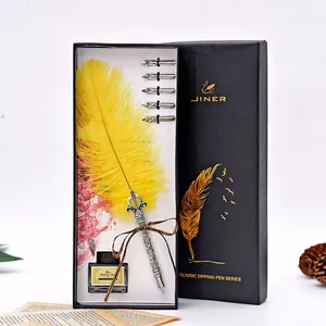 Detailed view of yellow feather quill pen set with five nibs and ink in a black gift box.