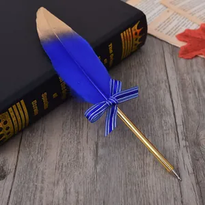 Detailed shot of a blue feather ballpoint pen with gold tip and bow on a book