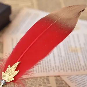 Dettaglio penna a sfera piuma rossa decorativa con foglia d'oro su carta vintage