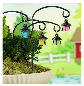 Detalle de pequeñas linternas luminosas colgando de estacas decorativas de hierro para jardín