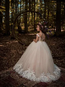 Detailed view of the elegant lace hem and long train of the white flower girl dress.