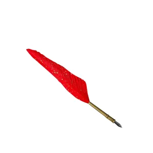 Vintage red feather quill dip pen with gold flecks and brass barrel on white background