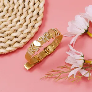 Close-up of gold mesh bracelet with rhinestone pavé GIRL lettering and heart charms