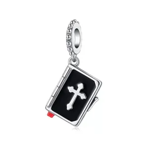 Close-up of a silver Bible charm featuring a black enamel cover and a silver cross